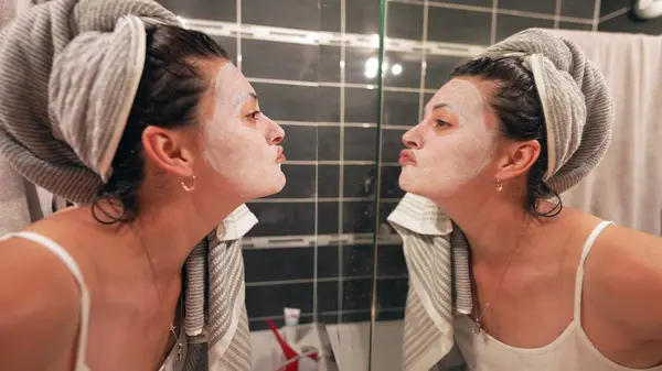 Frau Blickt Nachts Vor Badezimmerspiegel Auf Gesichtsmaske — Stockfoto