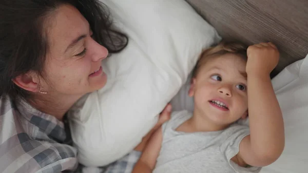 Family moment between mother and child in morning bed showing love and affection waking up