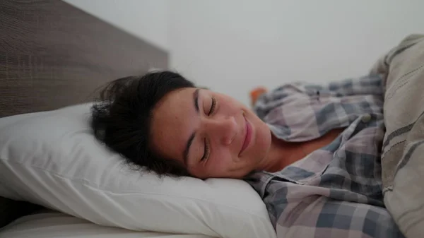 一个快乐的女人躺在床上 把头靠在枕头上 — 图库照片
