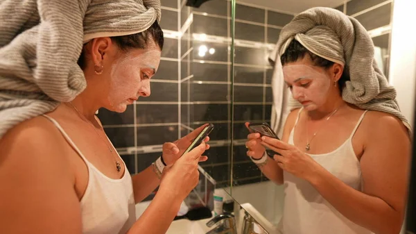 Frau Nach Bad Mit Gesichtsmaske Vor Badezimmerspiegel Telefoniert — Stockfoto
