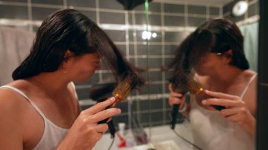 Kadınlar saçlarını banyo aynasının önünde kurutur.