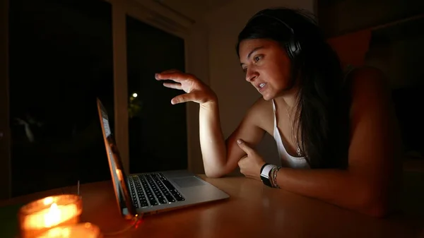 Person talking in front of computer screen at night woman in video communication with family