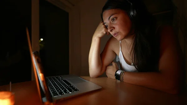 Person talking in front of computer screen at night woman in video communication with family