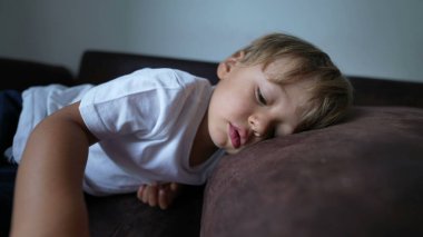 Çocuk kanepeye uzanıp dinleniyor. Çocuk kanepeye uzanıyor ve kestiriyor.