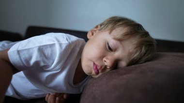 Çocuk kanepeye uzanıp dinleniyor. Çocuk kanepeye uzanıyor ve kestiriyor.