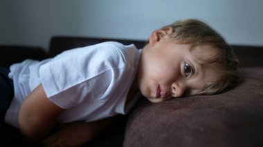 Çocuk kanepede dinleniyor. Huzurlu küçük çocuk uyumaya hazırlanıyor.