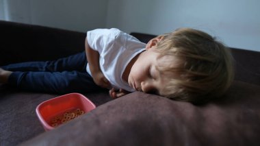 Çocuk kanepeye uzanıp dinleniyor. Çocuk kanepeye uzanıyor ve kestiriyor.