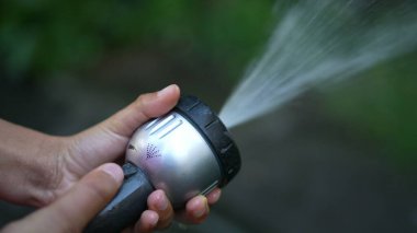 İtfaiye hortumunu tutan, suyu sulayan bahçenin yakınına.