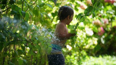 Çocuk dışarıda su püskürterek gülüyor ve gülüyor.