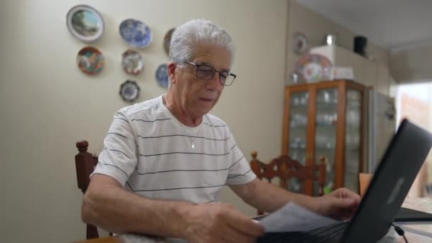 Ανήσυχος Ηλικιωμένος Που Κοιτάζει Ένα Καλό Χαρτί Μπροστά Στον Φορητό — Αρχείο Βίντεο