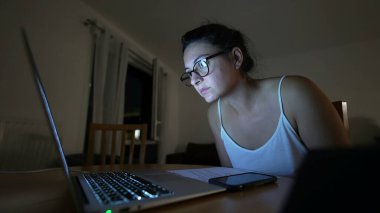 İnternette içerik okuyan bir kadın, gece vardiyasındaki bilgisayarına bakıyor.