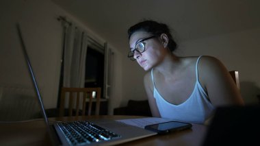 İnternette içerik okuyan bir kadın, gece vardiyasındaki bilgisayarına bakıyor.