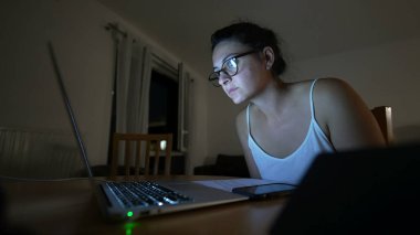 İnternette içerik okuyan bir kadın, gece vardiyasındaki bilgisayarına bakıyor.