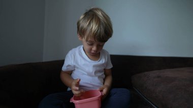 Küçük çocuk kanepede yemek yiyor.