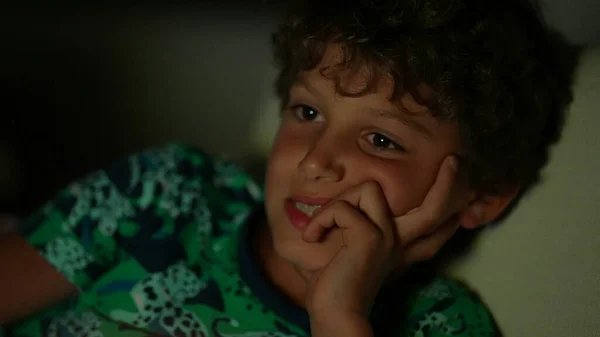 Small boy watching television screen at night