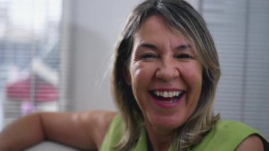 50 'li yaşlarda, kameraya gülümseyen orta yaşlı bir kadının portresi, beyaz bir kadının yakın plan yüzü.