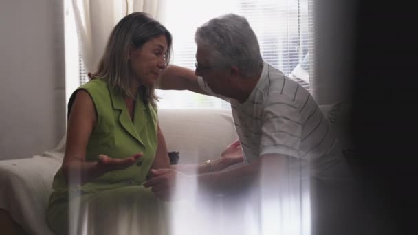 上了年纪的男人坐在沙发上 抱着成熟的女人 深情地拥抱在家里 长者互相支持 互相帮助 互相帮助 — 图库视频影像