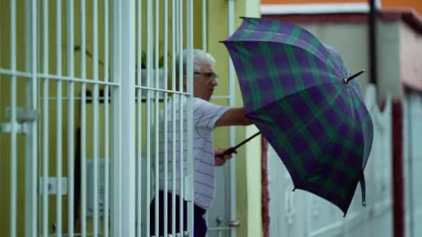 Пожилой Человек Выходит Дома Разворачивает Зонтик Охраняет Ворота Продолжает Идти — стоковое видео