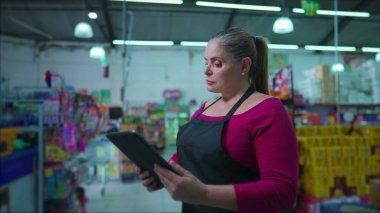 Süpermarket zincirinin sahibi kadın girişimci. Tablet cihazının sahibi. Duyguları nötr olmaktan mutlu iş dünyasına dönüştürüyor. Modern teknoloji kullanan orta yaşlı bir kadın.