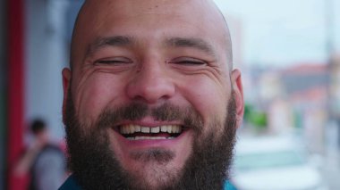 Sokakta gülümseyen mutlu sıradan bir adam. Neşeli, cesur, sakallı, sıradan bir erkeğin yakın çekimi.