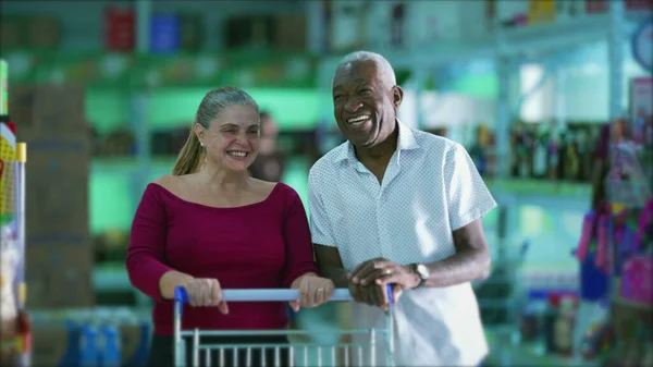 Happy diverse customers smiling inside grocery business store with shopping cart