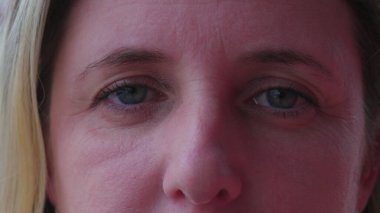 40 'lı yaşlarda kameraya bakan bir kadının makro yakın çekimi. Orta yaşlı beyaz bir kadın dik dik bakıyor.