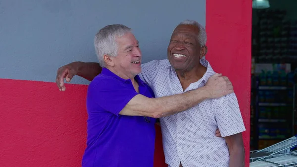 stock image Two happy diverse older friends hugging and celebrating with high-five standing outside on sidewalk. Cheerful African American and caucasian companionship authentic interaction