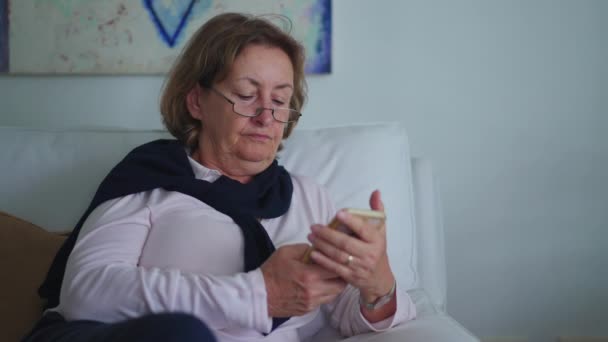Mujer Mayor Sosteniendo Teléfono Sentado Sofá Casa Navegar Por Internet — Vídeo de stock