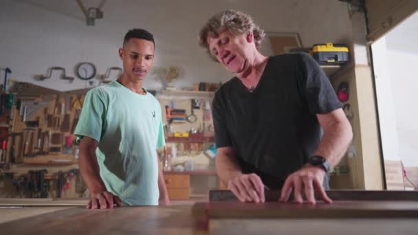 Master Carpenter Bekerja Bengkel Kayu Dengan Murid Mudanya Menunjukkan Bagaimana — Stok Video