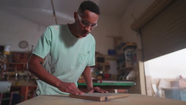 Один Молодой Черный Плотник Использует Машину Обрезать Кусок Дерева Мастерской — стоковое видео