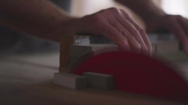 Usta Marangoz marangozluk atölyesinde testereyle odun buduyor. Kıdemli adam işiyle meşgul.