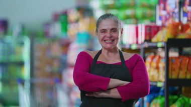 Neşeli Kadın Market İşçisi Kameraya gülümseyen, kollarını kavuşturan, önlük takan