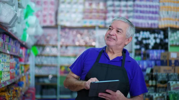 Joyful Senior Grocery Store Manager Checking Product Inventory on Shelf with Tablet Device, Caucasian Male Employee Inspecting Items at Supermarket Aisle