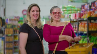 Markette elinde sepetle bekleyen iki mutlu bayan müşteri. Süpermarkette gülümseyen kadın portresi