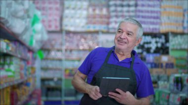 Marketin kıdemli müdürü, raflarda bulunan ürünlerin envanterini kontrol ediyor, beyaz bir erkek, süpermarket koridorunda ürünleri denetliyor.