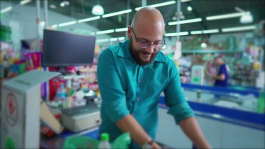 Checkout Tarayıcı ve Torbalama Ürünleri 'nde neşeli Brezilyalı süpermarket çalışanı, Güney Amerika Market Sahnesi' nde Gülümseyen Kamera