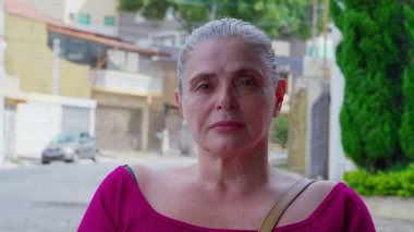 Olgun, sıradan bir kadın portresi, ciddi bir ifadeyle caddede duruyor. 50 'li yaşlarda beyaz kadın.