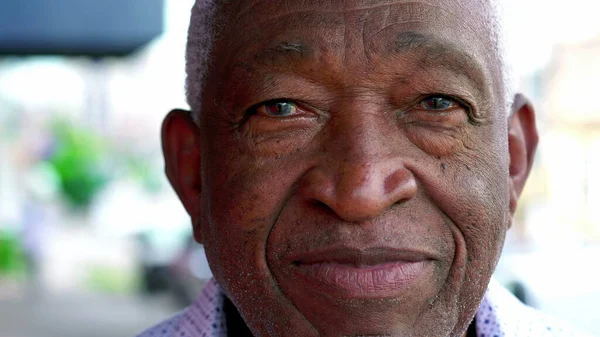 Close-up face of an African American elderly person looking at camera with neutral expression. A black senior Brazilian male person
