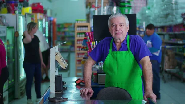 Starszy Pracownik Supermarketu Stoi Przy Kasie Neutralnym Poważnym Wyrazem Twarzy — Zdjęcie stockowe