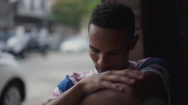 Depresyondaki genç siyah bir adam sosyal izolasyon ve zihinsel hastalıkla mücadele ediyor, yüzünü utanç ve pişmanlıkla örtüyor. Afrika kökenli Amerikalı sessiz umutsuzlukla karşı karşıya.