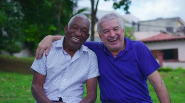 Yaşlı Kafkasyalı ve Afrikalı Amerikalı Dostlar Park Bench 'te Mutlu Anlar' ı birlikte gülüp gülüyorlar. Arkadaşı kollarına aldı.