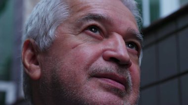 Son sınıf öğrencisinin UMUT ve FAITH ile gökyüzüne baktığı yakın çekim yüzü. Dindar, dindar, yaşlı bir insan, başını yukarı kaldırıyor ve gülümsüyor.