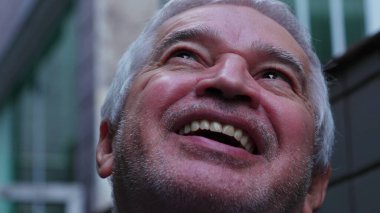 Son sınıf öğrencisinin UMUT ve FAITH ile gökyüzüne baktığı yakın çekim yüzü. Dindar, dindar, yaşlı bir insan, başını yukarı kaldırıyor ve gülümsüyor.