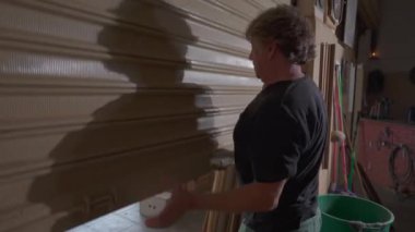 Yerel işletme sahibi, marangozhanenin sürgülü garaj kapısını açıyor.