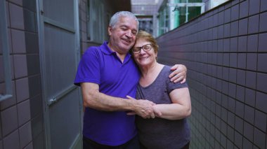 Arka bahçedeki koridorda kucaklaşarak gülümseyen yaşlı bir çiftin portresi. Yaşlı evli karı koca, yaşlılıkta hassas anlar, uzun süreli evlilik.