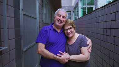 Arka bahçedeki koridorda kucaklaşarak gülümseyen yaşlı bir çiftin portresi. Yaşlı evli karı koca, yaşlılıkta hassas anlar, uzun süreli evlilik.