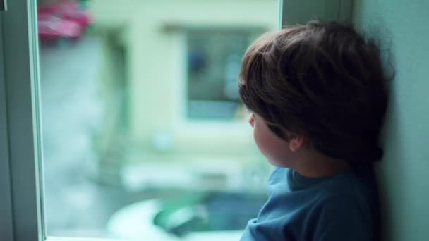 Pensive Little Boy Zittend Door Appartement Raam Staren Uit Zoek — Stockvideo