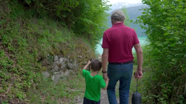 グランドソンと祖父の家族ハイキングシーン トレイルで手を握る 子供とおじいちゃんの間の愛する瞬間 — ストック動画