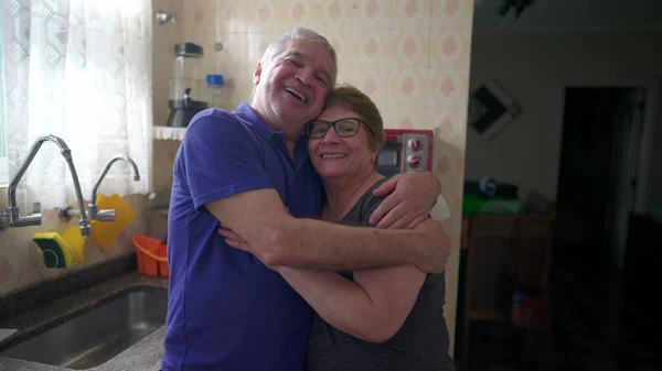 Счастливая Супружеская Пара Обнимается Дома Кухонной Раковины Портрет Пожилых Случайных — стоковое фото