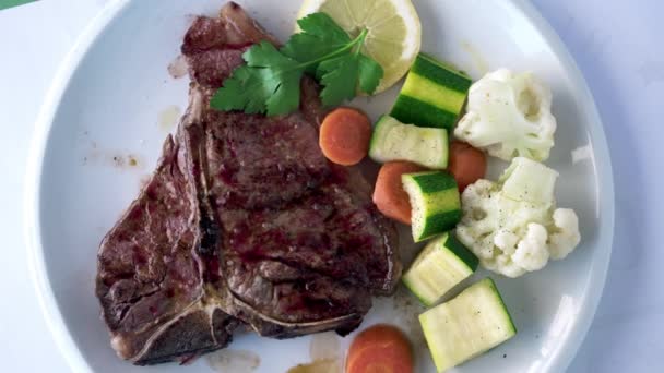 多汁的牛排 盘中有豆科植物 顶部的肉食与花椰菜 胡萝卜 西葫芦 美味蛋白质丰富的食物 — 图库视频影像